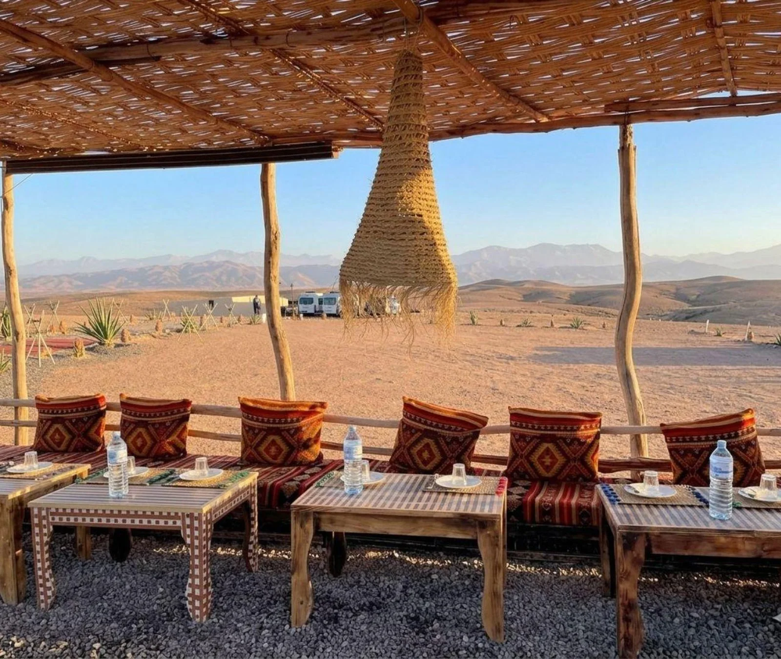 Several low dining tables set for guests under a desert camp canopy