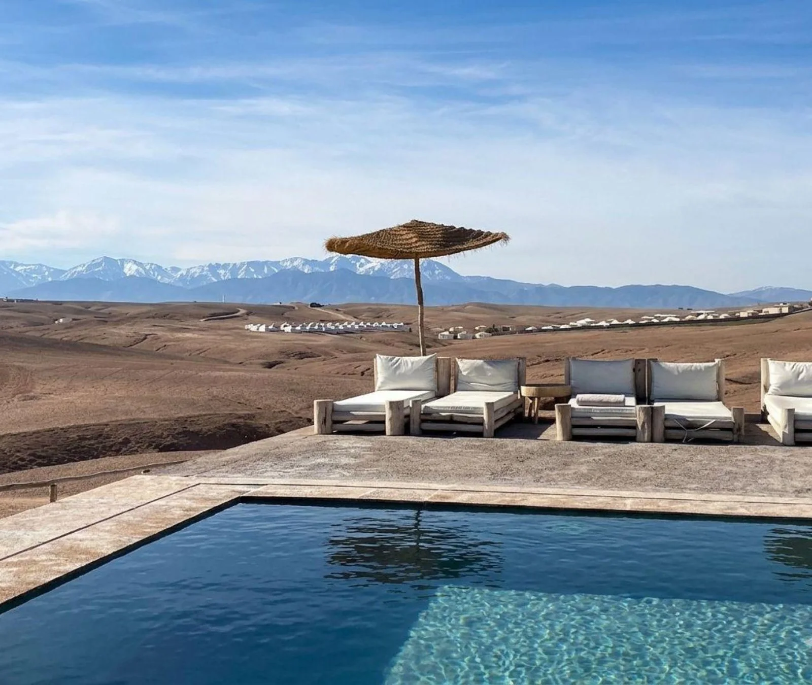 Poolside loungers with a view of the snow-capped Atlas Mountains from the Agafay Desert